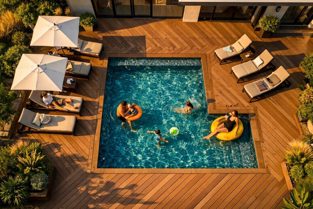 نمای هوایی استخر با کف‌پوش چوب پلاست و فضای استراحت خانوادگی